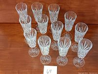 Twelve vintage cut crystal champagne stem glasses arranged in rows showing bowls and stems.