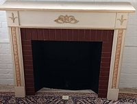 Wooden fireplace mantle with cream and gold detailing over brick fireplace opening.