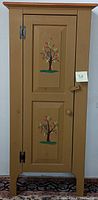 Front view of vintage wooden cabinet with hand-painted tree designs on door panels.
