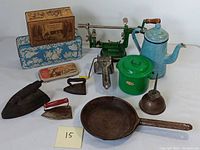 Full group photo of vintage kitchenware and collectibles including tins, cast iron cookware, apple peeler, oil can, and coffee pot.