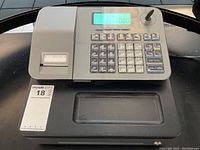Front view of Casio electronic cash register showing numeric keypad, function keys, display, and receipt printer along with a key inserted in lock.