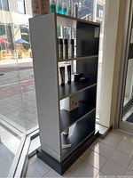 Side angle of the shelving unit displaying shelves with hair and grooming products.