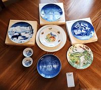 Photo showing seven collector plates, several Wedgwood blue and white Christmas collector plates, one colorful fruit design plate, and one nature scene plate.