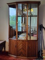 Front view of wood and glass display cabinet showing glass doors, interior shelves, mirrored back and crown molding
