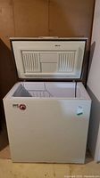 Front view of white Kelvinator Masterpiece chest freezer with lid open, showing interior basket and empty freezer compartment.
