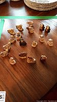 Photo showing a collection of small ceramic figurines arranged on a wooden surface, including animals and character figures, approximately 2 inches tall.
