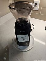 Front angled view of black Baratza Encore coffee grinder with clear hopper on countertop.