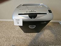Front view of the Fellows Crosscut Paper Shredder showing the top silver panel and black pull-out waste bin with a MaxSold number 18 tag.