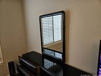 Gloss black dresser with a sheen finish, topped with a gloss black framed mirror with rounded corners.