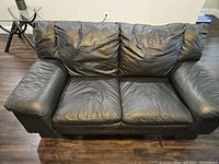 Full front view of black leather loveseat