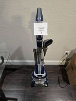 Front view of Shark Navigator NV360 upright vacuum cleaner standing on floor, showing hose and brush attachment, power cord, and control panel.