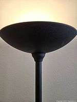 Close-up of the wide, shallow black metal torchiere lampshade showing even light diffusion.