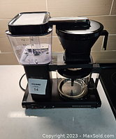 Front view of MochaMaster KBGV coffee maker showing water reservoir, filter basket, and glass carafe.