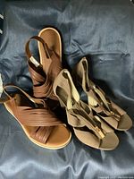 Two pairs of ladies shoes: flat brownish-beige sandals and beige high heel sandals with front zipper, shown from top view