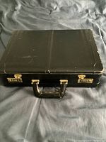 Closed black briefcase showing gold combination lock and handle.