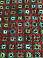 Close-up photo showing the multicoloured granny square pattern in detail with red and green borders.
