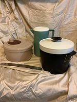 Three kitchen items: ice bucket, salad spinner, and juice container displayed together