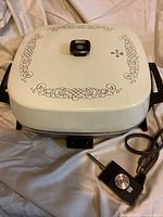 Photo of the beige dome lid with decorative scrollwork and black handle knob, showing General Electric electric skillet.