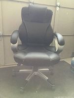 Front view of the black leather office chair showing padded seat, armrests, and five-wheel base.