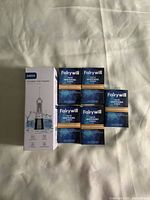Photo of the ABOX Portable Oral Irrigator box and five Fairywill teeth whitening strip packages arranged on a surface.