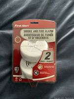 Front view of the 2-pack First Alert smoke and fire alarms in original sealed packaging showing branding, product name, and key features.