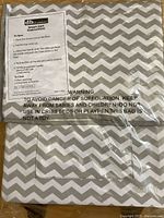 Fabric bag folded with instruction label and safety warning visible, pattern gray and white chevron.