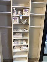 Full view of shelving showing Wamsutta bathroom ceramic accessories, towels, shower curtain, and ceramic basket on white shelves