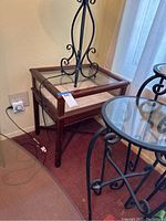 Square wooden side table with glass display case top visible from an angle, showing the wood frame, glass on top, and part of the beige interior