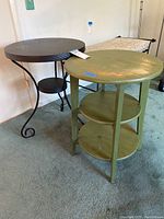 Photo showing black metal Ikea table and green wooden three-tier table side by side.