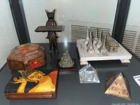 View of all items in the lot showing three pyramids, bronze fox business card holder, two Asian wooden trinket boxes, and the Hen Feathers tic-tac-toe game.