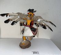 Full front view of the 13-inch tall Kachina doll with feathered wings outstretched, standing on a wood base.