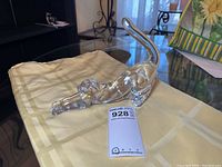 Lenox clear crystal cat figurine in stretching pose on light-colored cloth, showcasing the full side profile of the cat