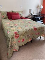 Bed made with green floral machine-quilted bed cover, matching shams, burgundy sheets, and pillows, showing front full bed view and bedding details.