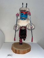 Front view of 20 inch vintage Deer Kachina doll with blue face mask and fur trim, mounted on a wooden base.