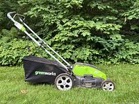 Full side view of the Greenworks electric lawnmower showing the grass collection bag and overall design.