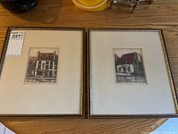 Pair of two framed hand-coloured engravings of Quebec buildings shown side by side on a wood surface.