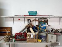 Photo of a shelving area with various tools, a metal toolbox, rope, chain links, and other hardware items.