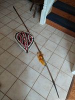 Wide shot showing both the leather shield and iron tipped spear on tiled floor