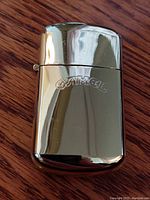 Front view of the shiny gold-tone Camel Gold flip lighter showing embossed 'CAMEL' logo.