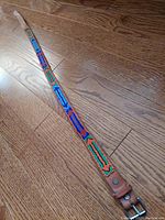 Photo showing the full length of the handcrafted beaded leather belt with bright beadwork patterns and a metal buckle end.