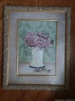 Framed mauve floral painting in ornamental gilt wood frame shown angled to display the painting and frame condition.