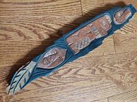 Top view of the elongated vertical cottonwood bark carving showcasing Thunderbird, Beaver, and Human figures in stylized tribal form with natural brown and black coloration on wood.