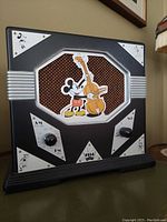 Front angled photo showing Mickey Mouse playing bass graphic on the speaker with black wood and silver metal accented radio body.