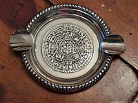 Front view of round tray showing central Mayan calendar design, rope-twist edge and two rim rests