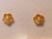 Close-up photo of the pair of flower-shaped earrings showing translucent mother of pearl petals and diamond centers