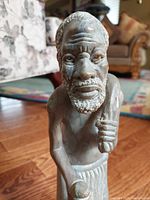 Front view focused on the detailed facial features and upper body of the West African Griot stone sculpture.