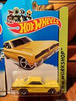 Close-up of yellow muscle car Hot Wheels in original packaging from the 1990s with blue card and Hot Wheels logo