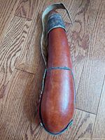 Full view of the elongated polished brown gourd water canteen laying flat on wood floor, showing shape and overall condition.