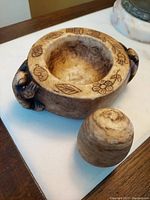 Angled top view showing mortar with etched decorations and one pestle beside it.