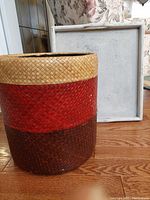 Image showing front view of the woven hamper basket beside the rectangular wooden tray resting vertically.
